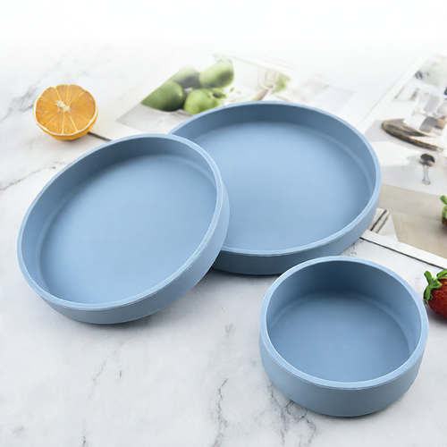 Set of three blue ceramic dishes on a marble surface with fruits in the background